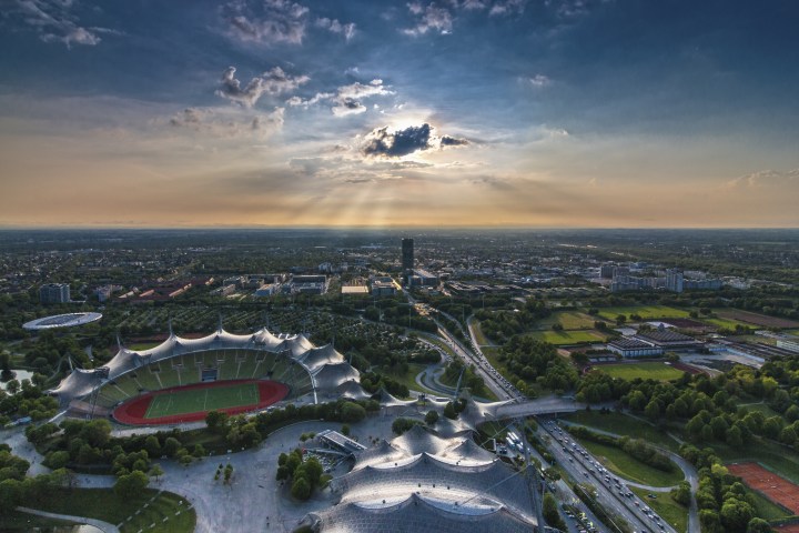 Aerial view of a stadium with a sunset and cityscape in the background.