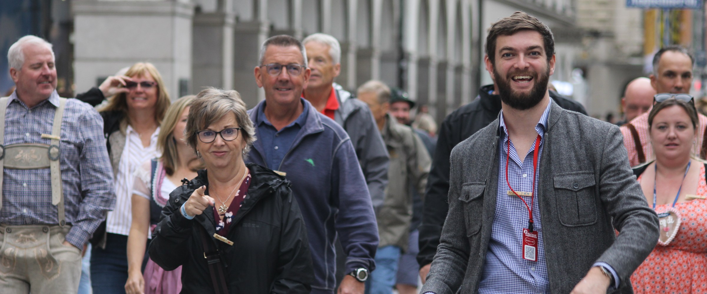 Group of people walking on a city street, some wearing traditional clothing.