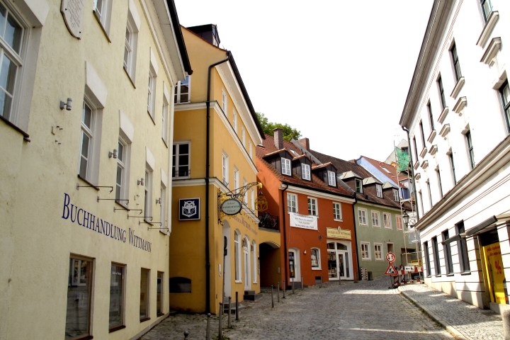 A sloped, cobblestone street lined with colorful, traditional European buildings.