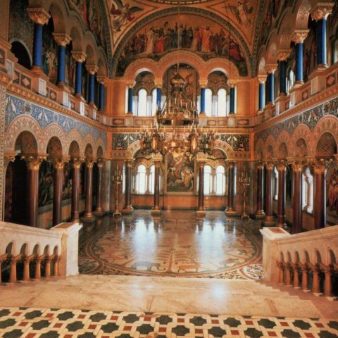 Ornate hall interior with frescoes, arched windows, and chandeliers inside Neuschwanstein