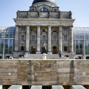 Historic building with columns and a statue in front, featuring glass windows and a dome.