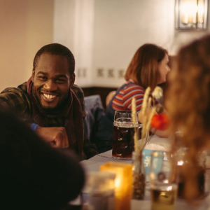 Smiling man in a dimly lit restaurant or bar with drinks on the table.