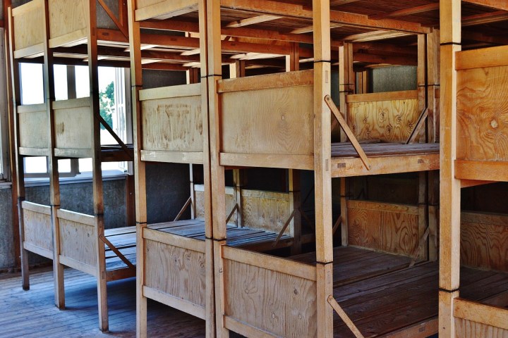 Wooden bunk beds in a compact room with natural light from windows.