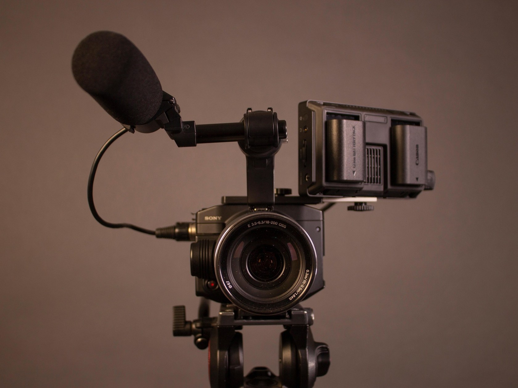 Professional video camera with attached microphone and external battery pack.