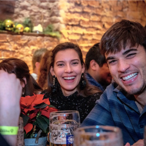 Smiling people in a bar with drinks and holiday decorations on a brick wall.