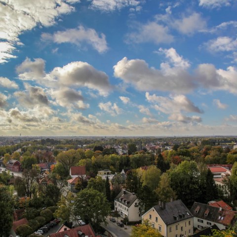 Aerial view of Dachau with trees, houses, and cloudy sky.