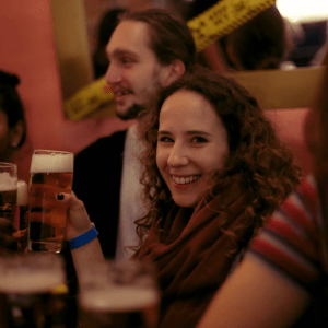 People enjoying drinks at a bar, with a smiling woman holding a beer.