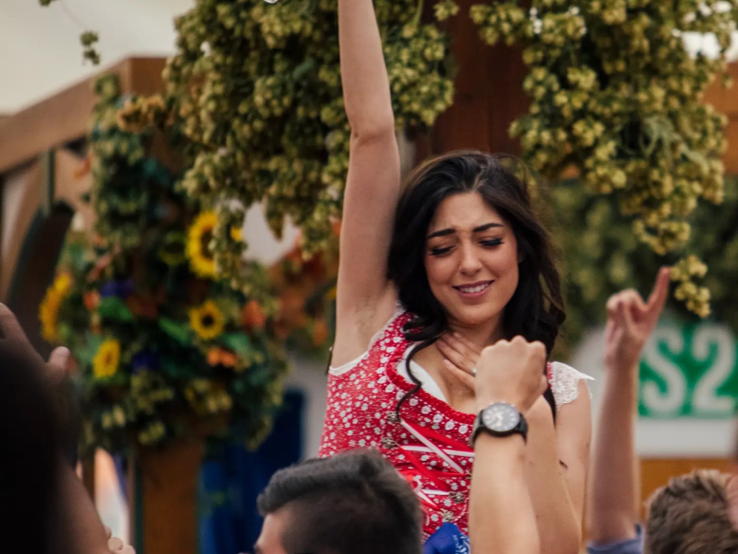 Woman in traditional dress holding empty beer mug, surrounded by cheering crowd.