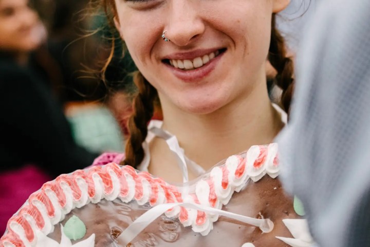 Smiling woman holding a heart-shaped gingerbread with 'Ich liebe Dich' written on it.