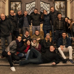 Group of people posing on stone steps in front of a building entrance.