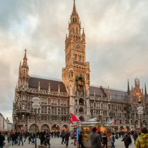 Crowd in front of ornate Gothic building at dusk with cloudy sky.