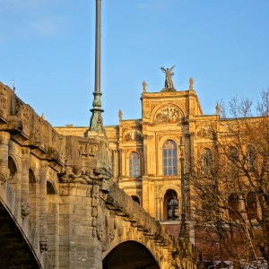 Stone bridge with ornate lamp post and historic building in background during sunset.