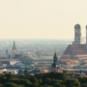 Panoramic view of a city skyline with historic towers and green foreground.