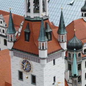Ornate building with red-tiled roofs, multiple spires, and a round clock face.