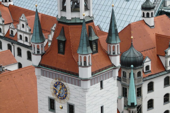 Ornate building with red-tiled roofs, multiple spires, and a round clock face.
