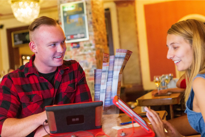 Two people smiling and talking at a table with game cards in a cozy room.