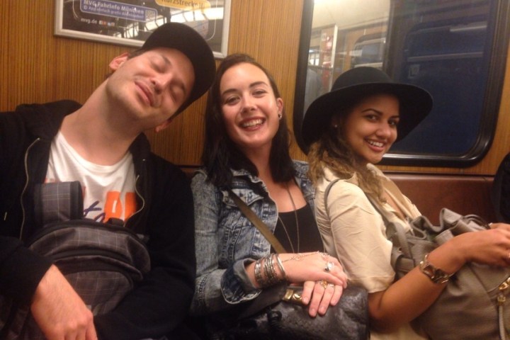 Three people smiling and sitting on a subway train.