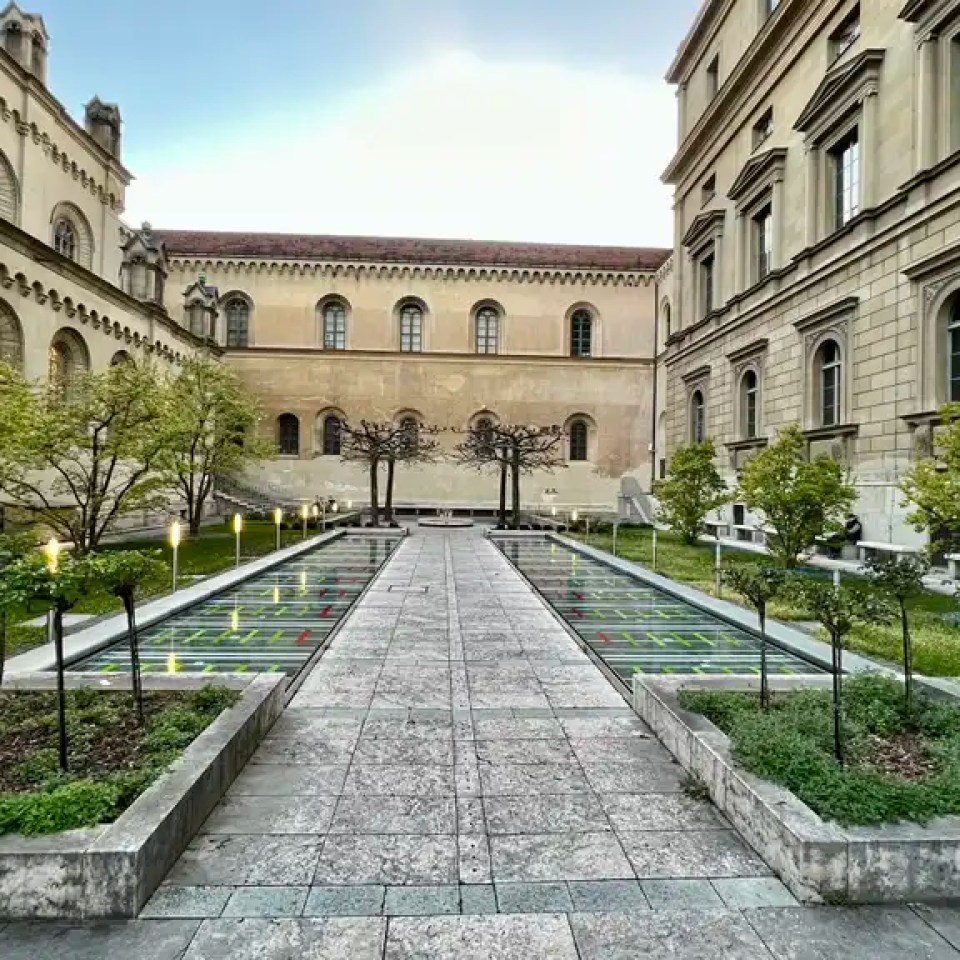 Courtyard with trees and a pathway between two historical buildings.